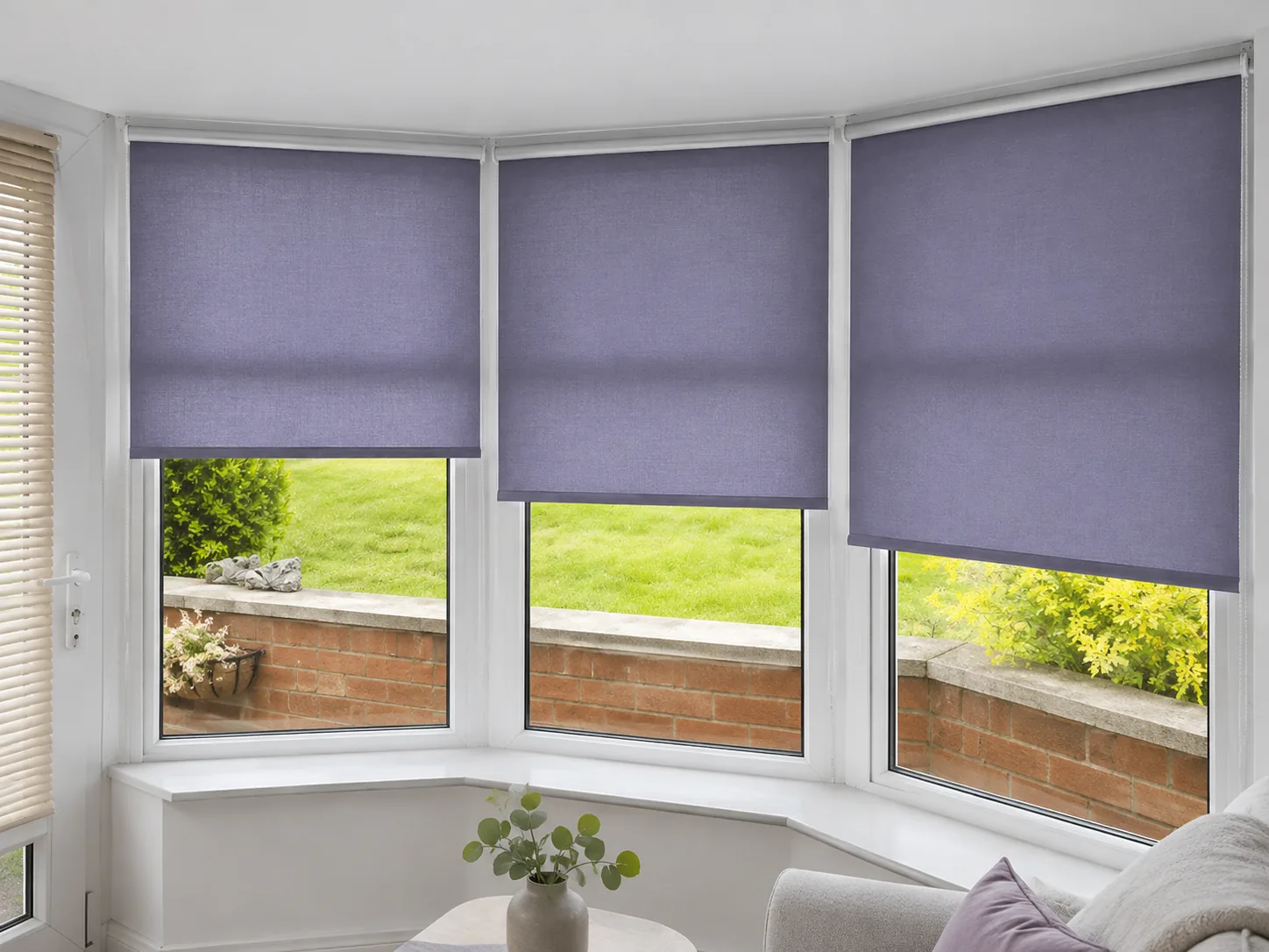 Purple roller blinds fitted across a bright three-panel bay window