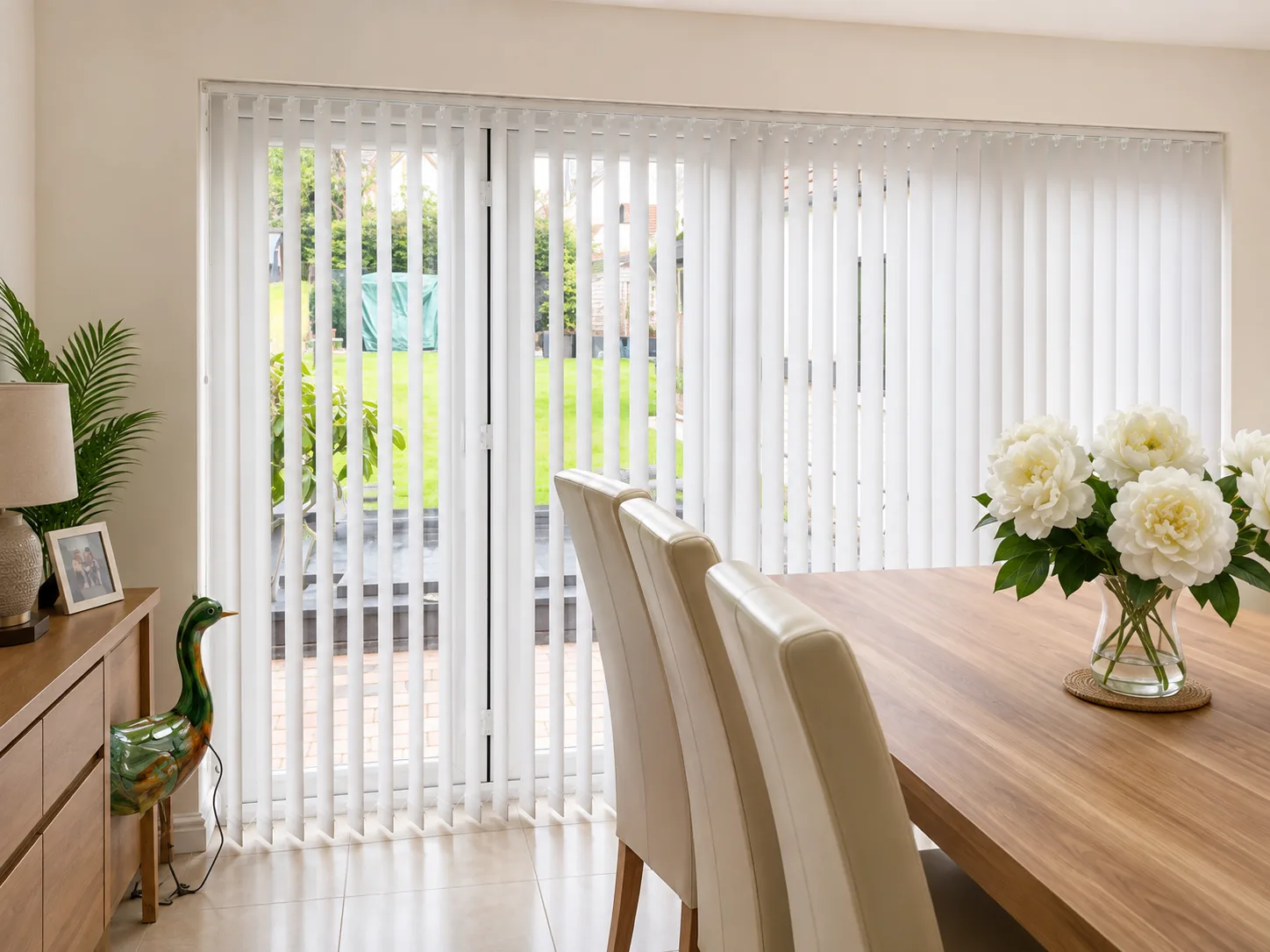 White vertical blinds fitted across patio doors in a bright dining room