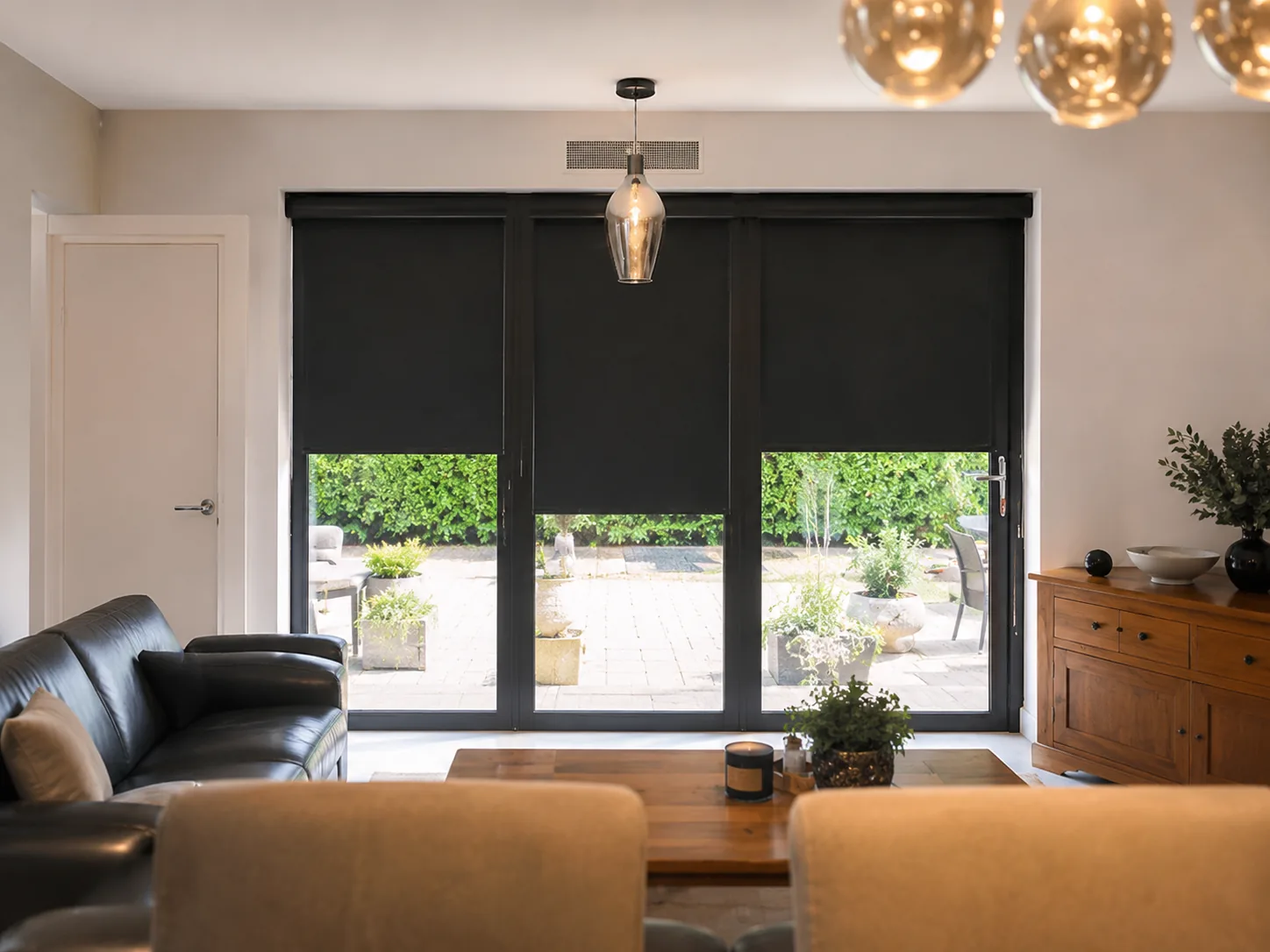 Dark roller blinds fitted across large glazed patio doors in a modern room