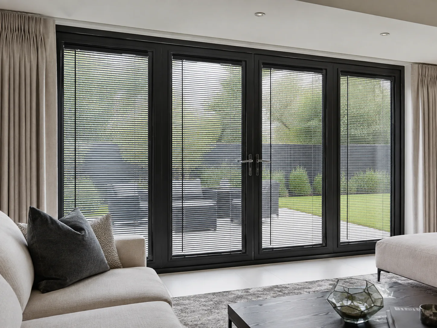 Dark Venetian blinds fitted across black-framed patio doors in a modern living room