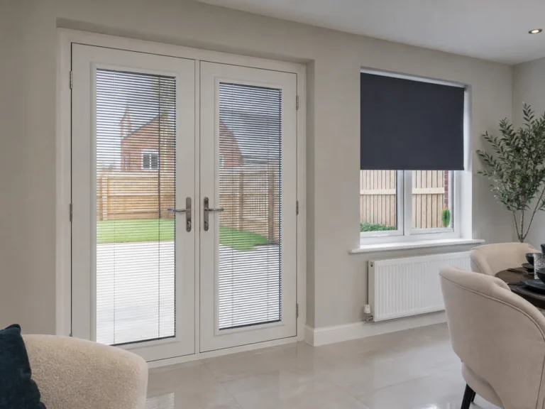 Slim fitted door blinds on white French doors beside a dark roller blind on a window